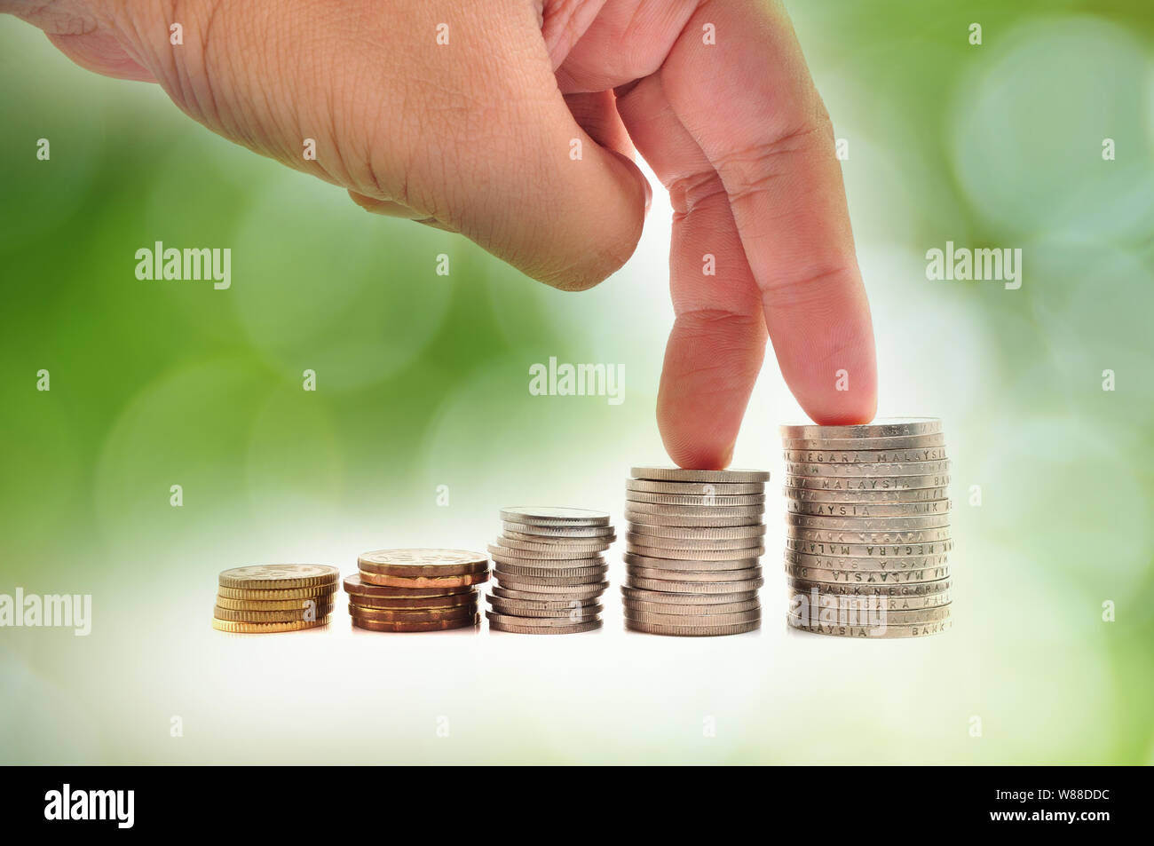 Concept de croissance. Les doigts à monter sur des piles de pièces de monnaie sur fond blanc Banque D'Images