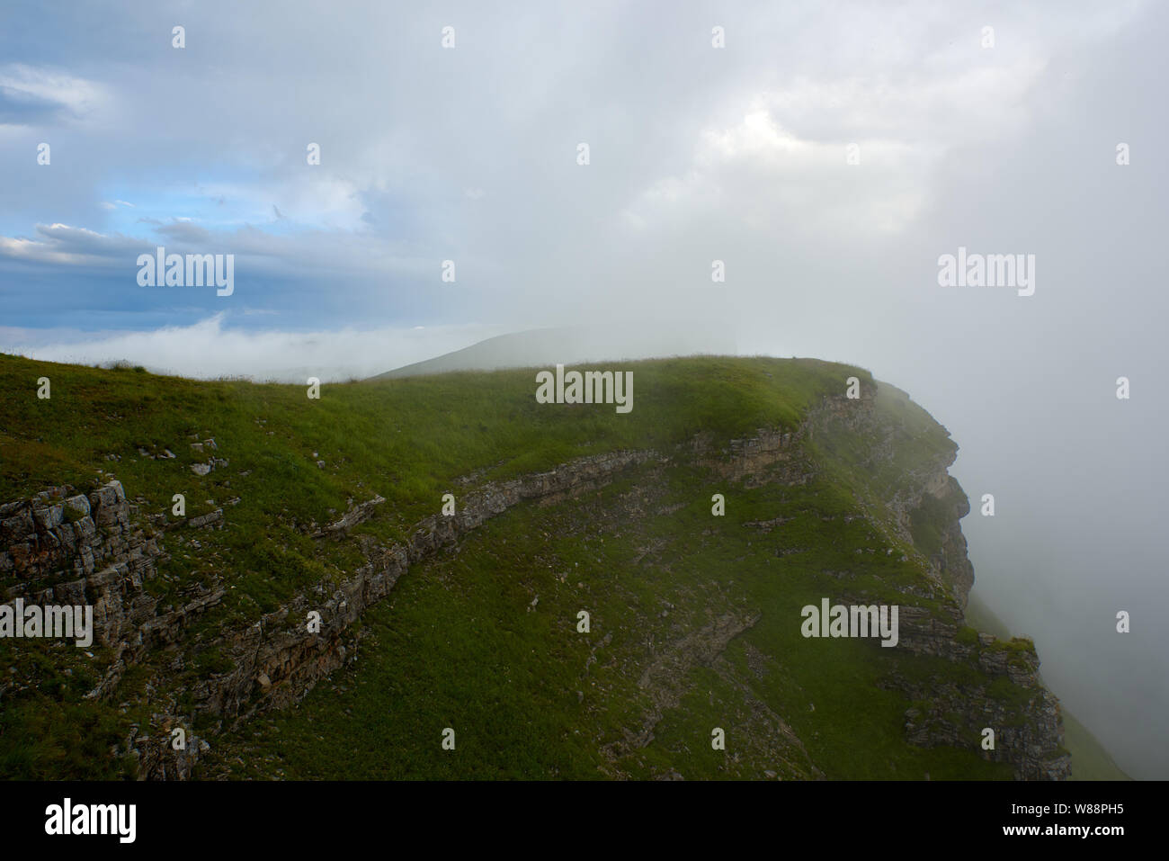 Gamme de montagne couverte d'herbe verte avec des pierres saillantes dans le brouillard. La Russie Banque D'Images