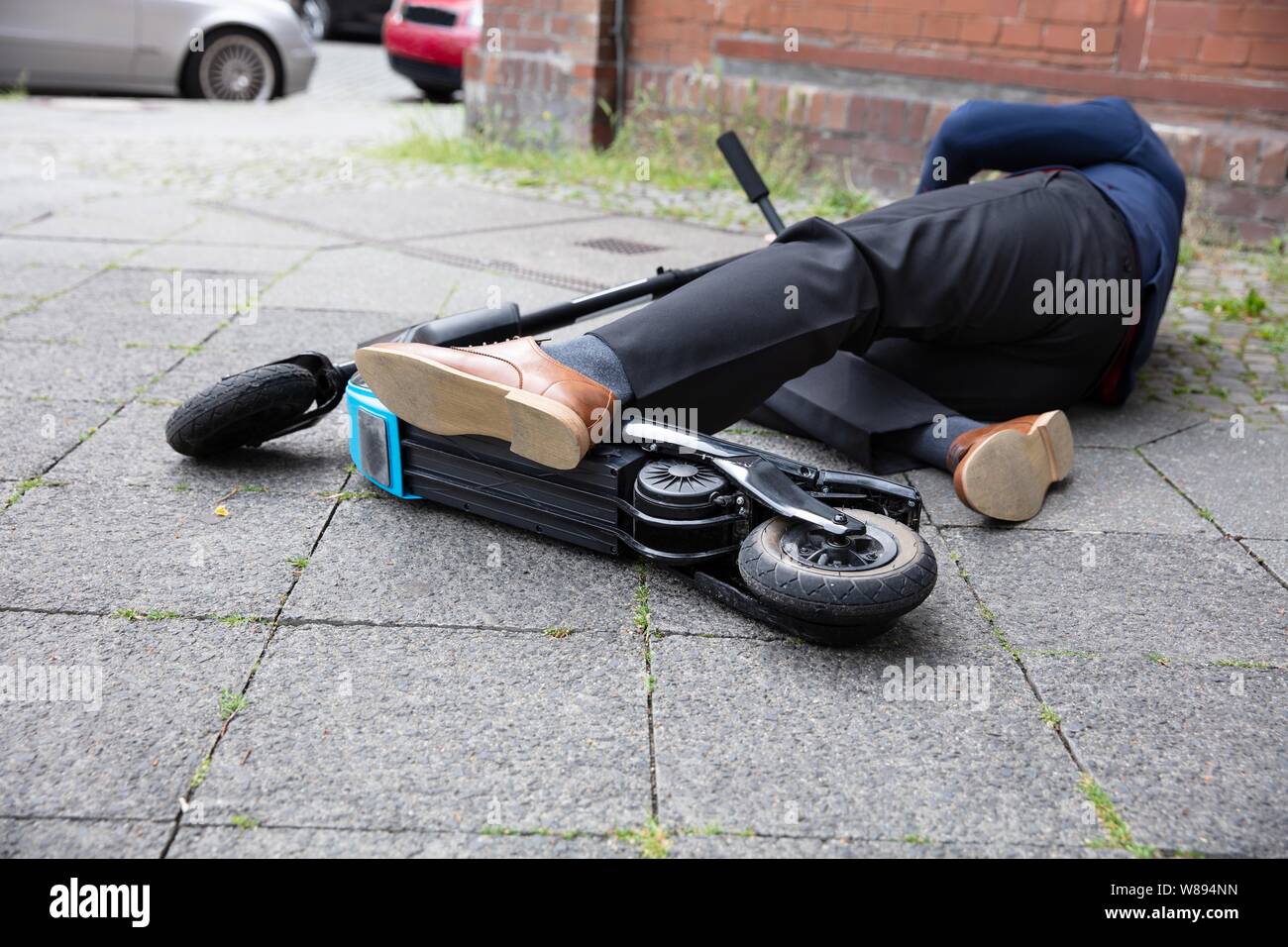 Homme inconscient allongé sur le béton rue après accident avec un Scooter électrique Banque D'Images