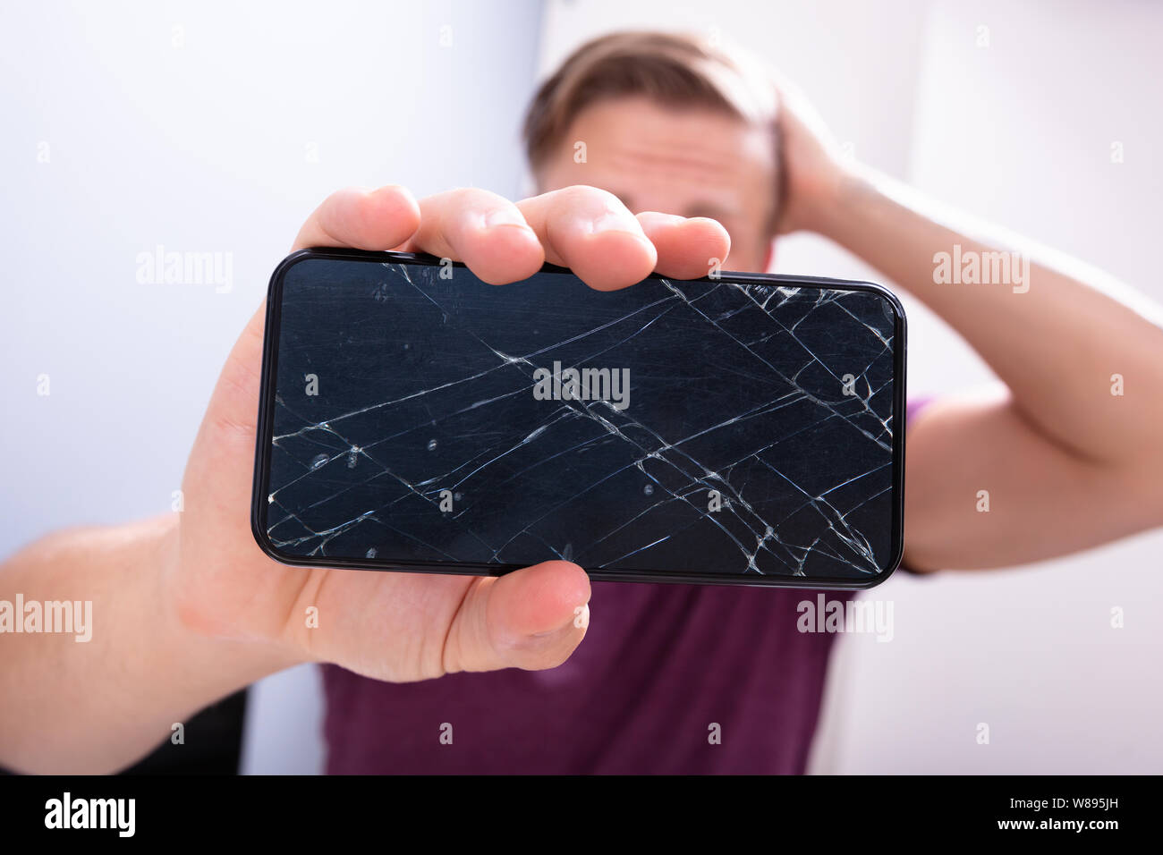 Inquiets Man Holding smartphone cassé à la maison Banque D'Images