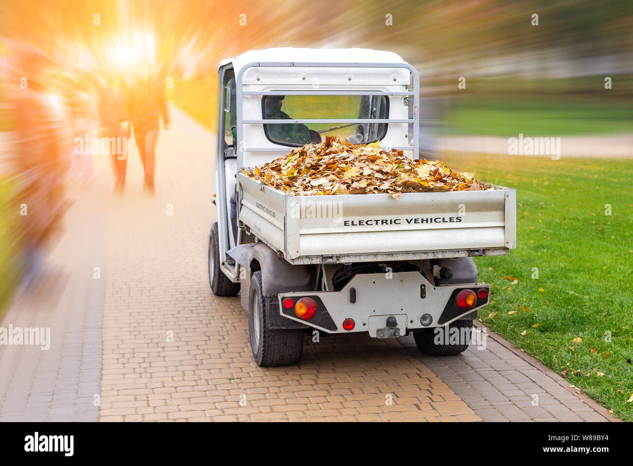 Petit chariot électrique suppression de feuilles tombées dans l'administration à l'automne parc de la ville. Les services urbains municipaux à l'aide de camion véhicule vert de l'écologie à la propreté des rues Banque D'Images