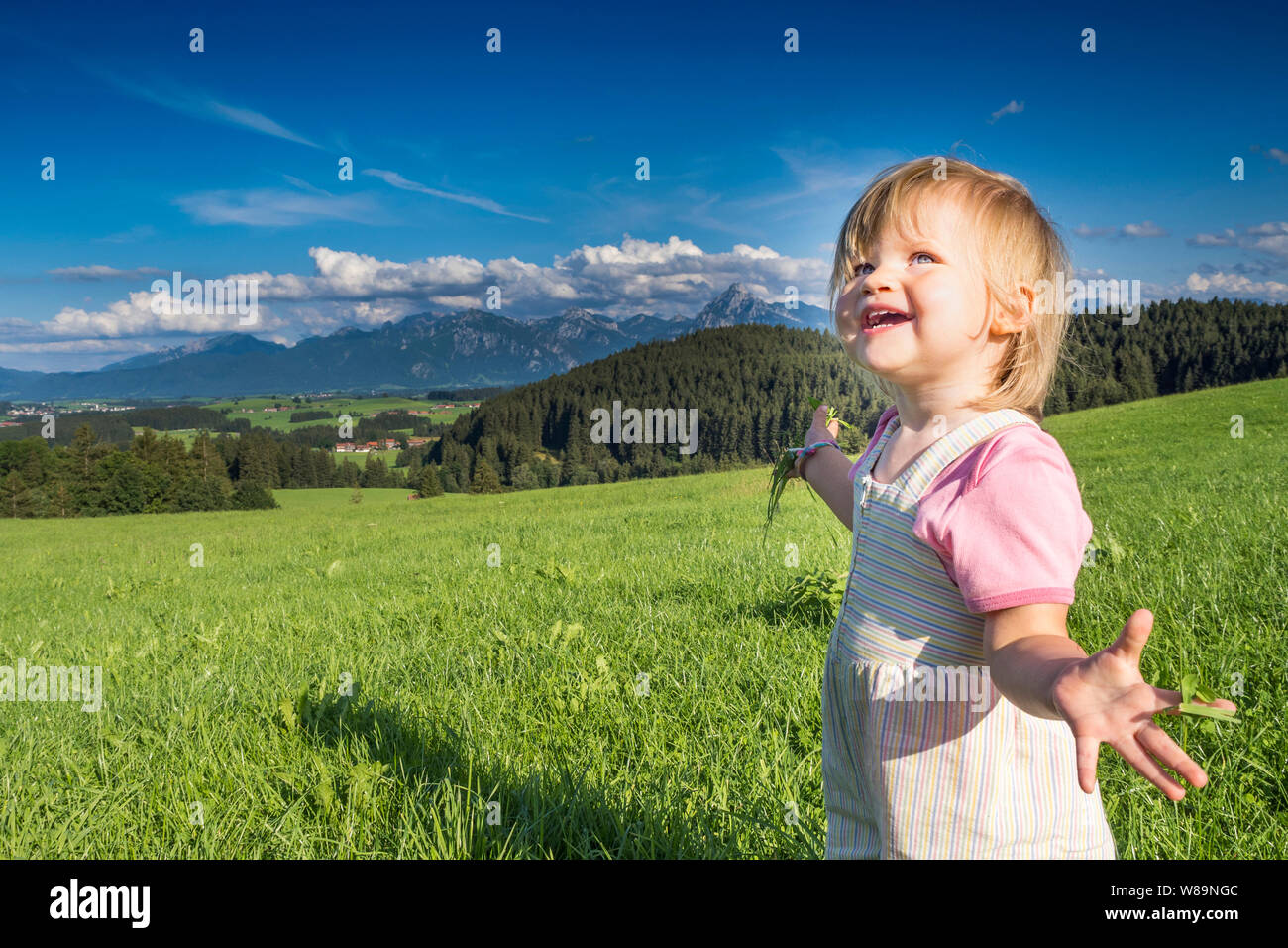 Allemagne, Bavière, Allgaeu, happy baby girl jouant dans les champs Banque D'Images