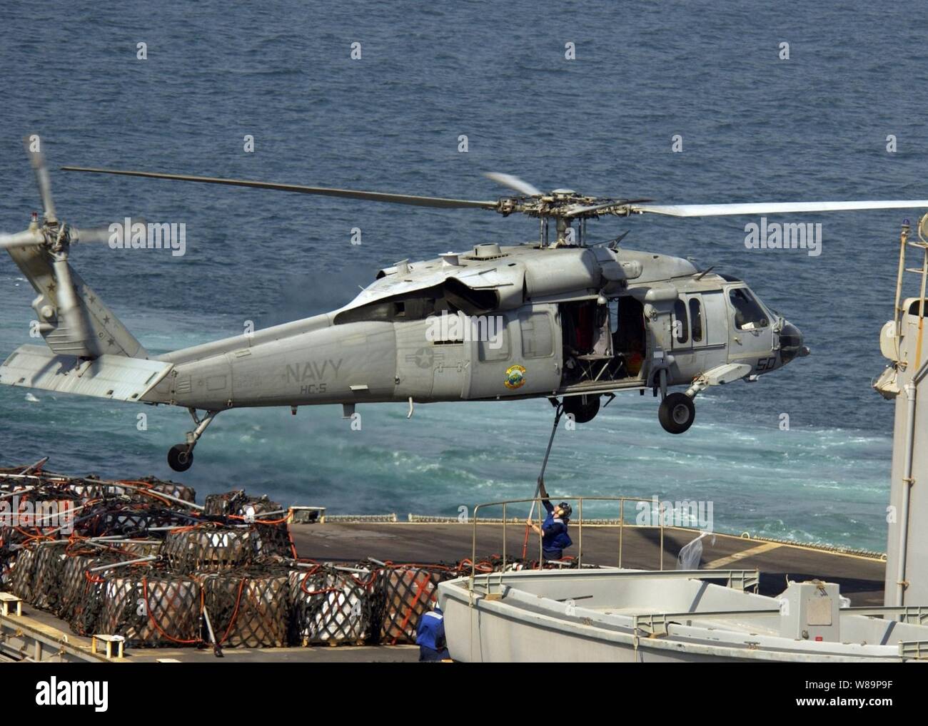 Un marin à bord du USS Seattle (AOE 3) attache une élingue de fret au crochet d'un SH-60 Seahawk pendant les opérations de ravitaillement vertical effectué avec l'USS Harpers Ferry (LSD 49) dans le nord du golfe Persique sur Septembre 22, 2004. Le Seahawk est affecté à l'Escadron de soutien de l'Hélicoptère 5. Le Seattle et Harpers Ferry fonctionnent dans le golfe Persique dans le cadre de l'opération Iraqi Freedom. Banque D'Images