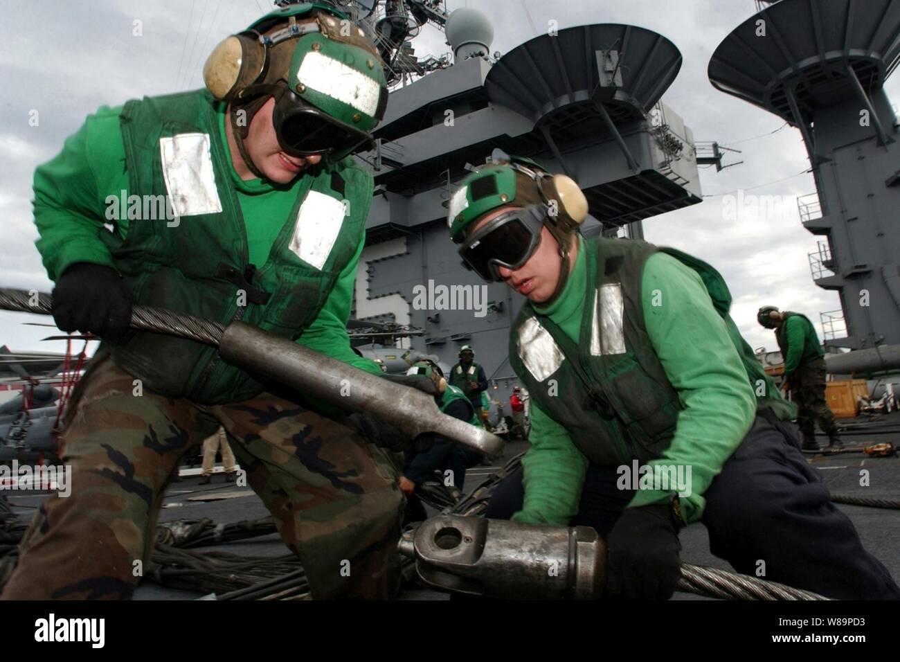 Aviateurs Brandon Davis (à gauche) et Zack St. Germaine brancher un fil de platine pendant l'arrestation de son achat de câble comme d'autres marins de la plate-forme d'atterrissage d'urgence au cours d'un exercice barricade sur le pont du porte-avions USS Harry S. Truman (CVN 75) Le 18 octobre 2004. Dans une situation d'urgence la barricade serait étendu sur le pont pour prendre un avion défectueux et d'assurer la sécurité du personnel navigant et l'équipage du transporteur. Le Groupe aéronaval Truman carrier mène des qualifications dans l'Est de l'océan Atlantique. Banque D'Images