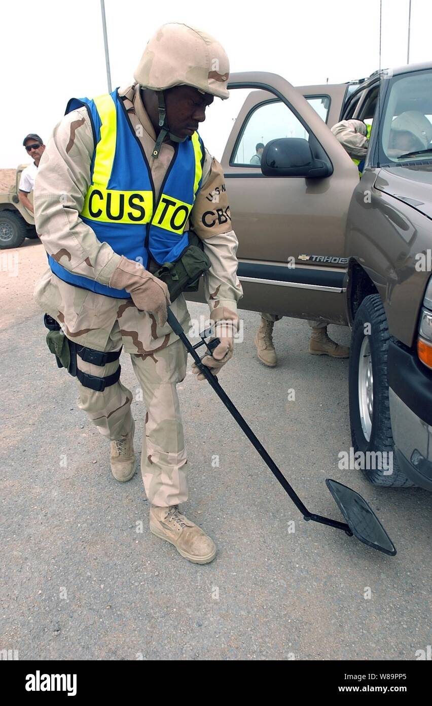 Le Maître de 2e classe de la marine Terrance Byrom utilise un miroir pour examiner la face inférieure d'un camion pendant un contrôle de sécurité près de la frontière entre le Koweït et au Camp Navistar, le Koweït, le 8 mars 2005. Byrom est une réserve de l'aviation de la marine 4400 machiniste affecté à l'appui logistique de la Marine Expeditionary Force, qui est l'exécution de la mission des douanes pour l'Armée américaine au Koweït et l'Iraq. Banque D'Images