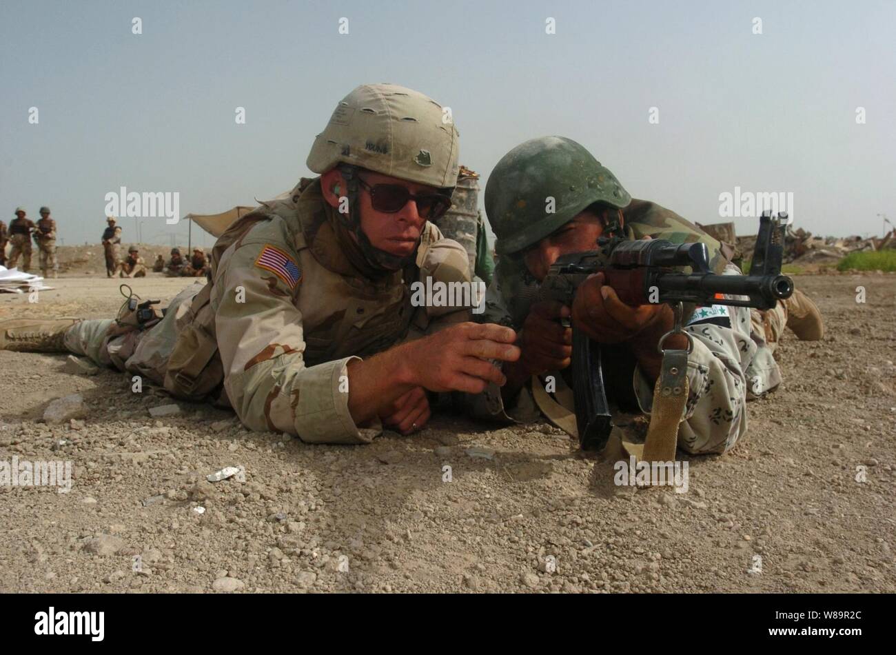 La CPS de l'armée américaine. John Young (à gauche) indique à un 8e soldat de l'armée iraquienne Division au cours d'un exercice de formation sur les armes à feu sur l'armée irakienne composé à base d'Ile, l'Iraq, le 28 juillet 2005. Young est membre de l'armée américaine équipe formation multinationale, une partie de l'155Th Brigade Combat Team, qui offre de la formation pour accroître la compétence des soldats de l'armée iraquienne. Banque D'Images