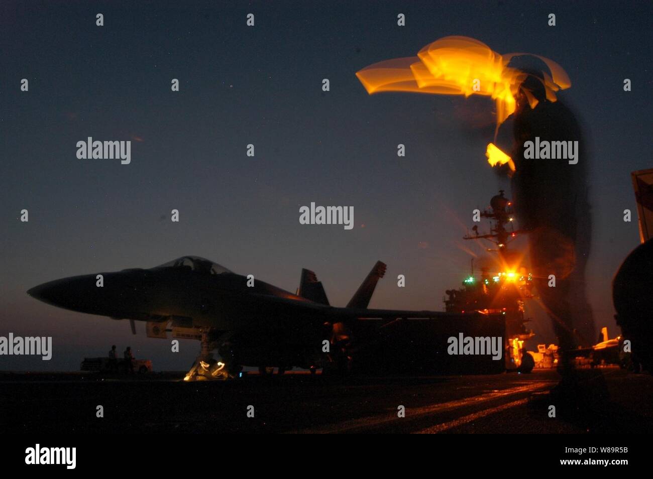 A l'aviation de la Marine américaine des signaux à un Manœuvrier Mate F/A-18E Super Hornet affectés à Strike Fighter Squadron 143 qu'ils sont clairs pour le décollage lors de la nuit à bord du porte-avions USS John F. Kennedy (CV 67) en cours dans l'Océan Atlantique sur Septembre 19, 2005. Banque D'Images