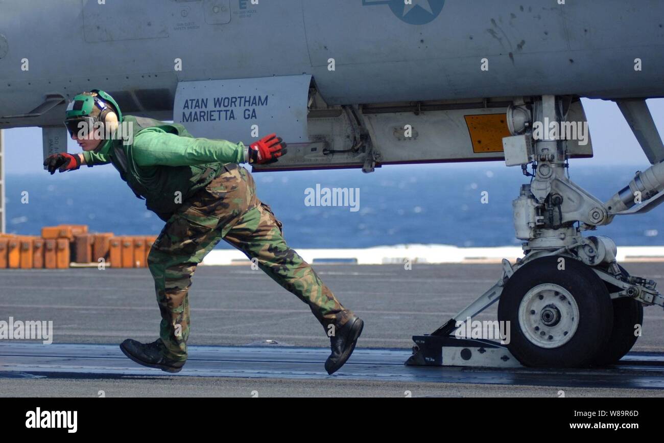 Un poste de pilotage de la Marine d'équipage s'exécute sous un avion après le raccordement à la catapulte sur le pont du porte-avions USS Harry S. Truman (CVN 75) le 15 octobre 2005. Truman mène des qualifications de l'opérateur et soutien la formation s'est lancé avec Carrier Air Wing 3 dans l'océan Atlantique. Banque D'Images