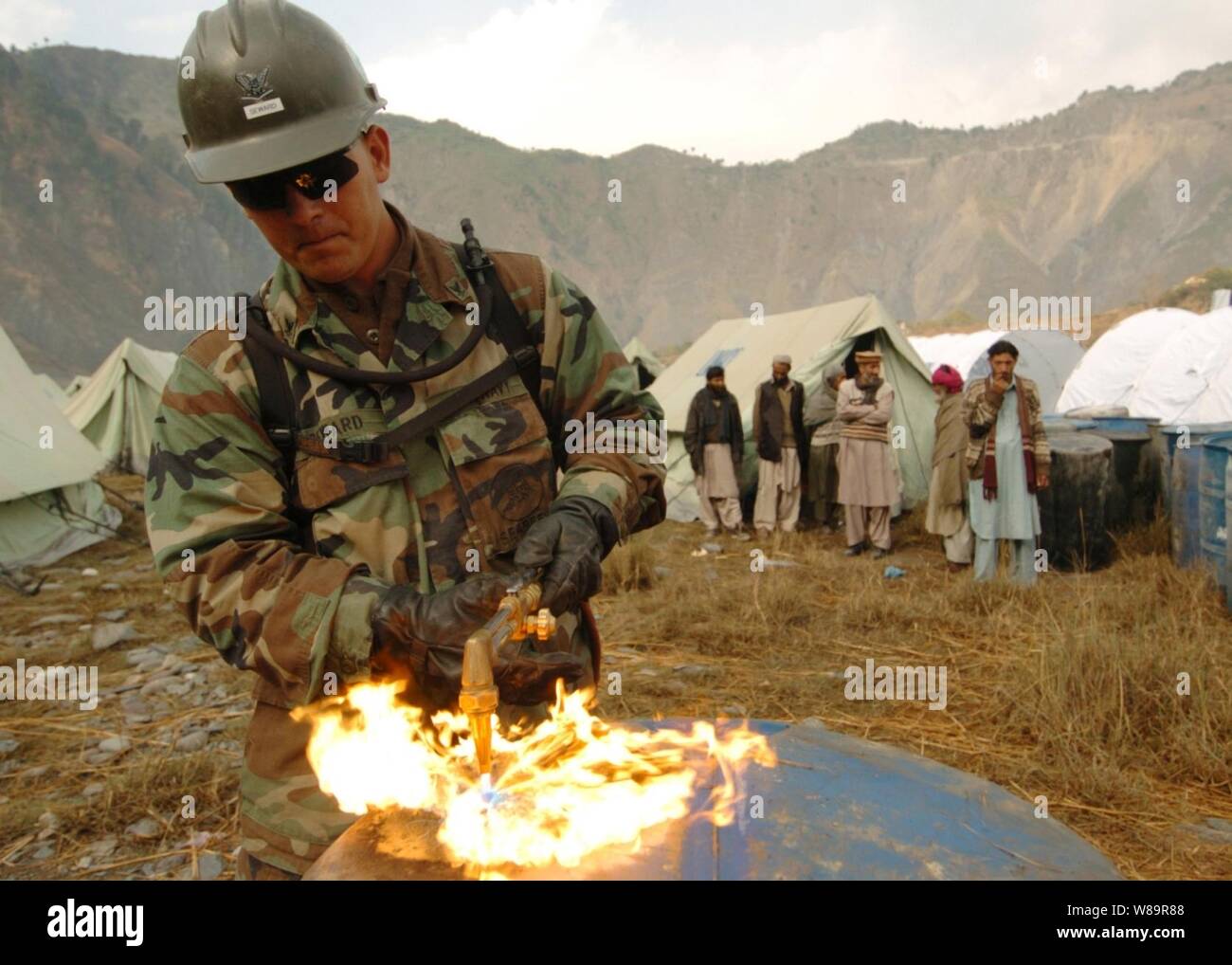 La Marine américaine, le Maître de 3e classe le Tchad Seward utilise un chalumeau pour couper à travers le baril comme Navy Seabees construire des latrines pour les familles déplacées à l'Thuri Park Village de tentes près de Muzaffarabad, Pakistan, le 11 novembre 2005. Seward est un métallurgiste naval de la Marine attaché à Mobile Construction Battalion 74, déployés à partir de Gulfport, Mississippi Le ministère de la Défense soutient le Département d'État par la fourniture de secours en cas de catastrophe des fournitures et des services à la suite du tremblement de terre qui a frappé le Pakistan et certaines parties de l'Inde et l'Afghanistan. Banque D'Images