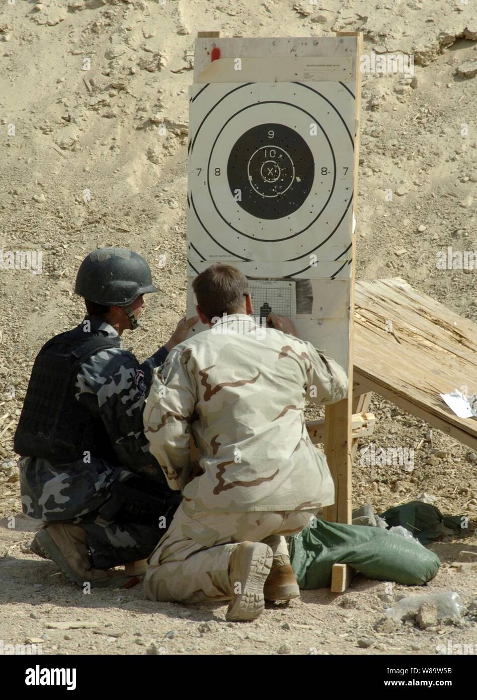 Un soldat de l'armée américaine (à droite), du 3e Bataillon, 10e Groupe des Forces spéciales reviews une cible tout en aidant un irakien d'armes spéciales et tactiques avec des membres de l'équipe observation correctement dans son arme au cours de l'entraînement au Camp touché, l'Iraq, le 26 août 2007. Banque D'Images