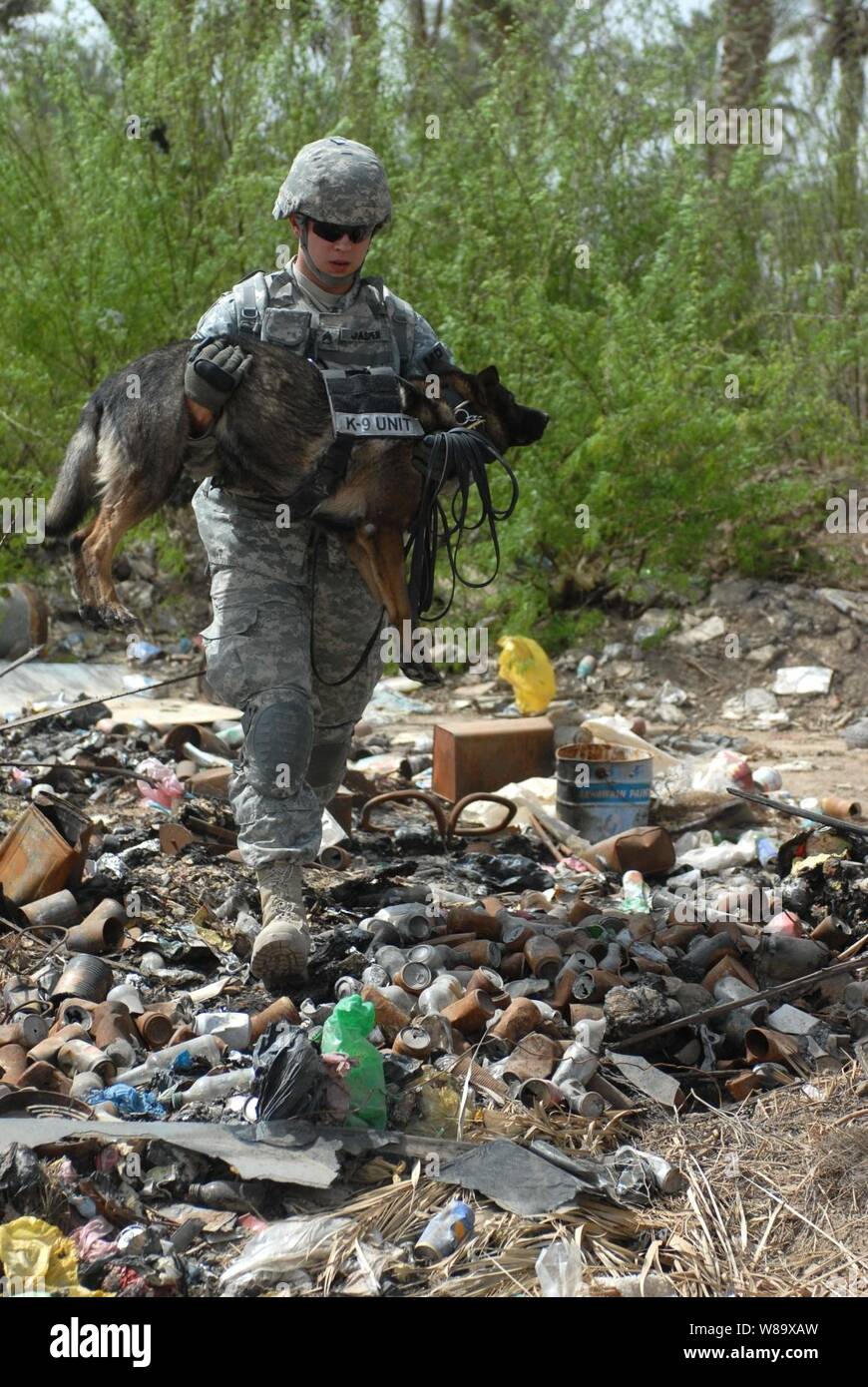 Le sergent de l'armée américaine. Evans de la 2e Brigade Combat Team, 1re Division d'infanterie porte Uwe, son chien de travail militaire, plus un dépotoir de la ville d'Abu Ghraib, en Irak, lors de la recherche de caches d'armes le 21 mars 2009. Banque D'Images