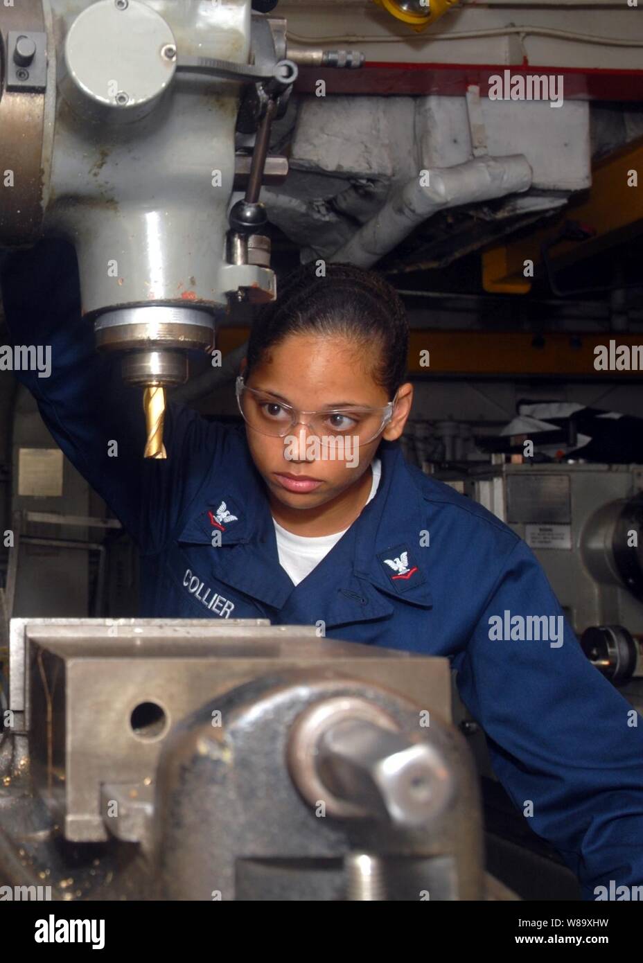 La Marine américaine, le Maître de 3e classe Valerie Collier s'occupe de l'entretien d'une machine de fraisage dans la boutique de machines à bord du navire d'assaut amphibie USS Essex (LHD-2) dans la mer de Chine orientale, le 17 juin 2009. Banque D'Images