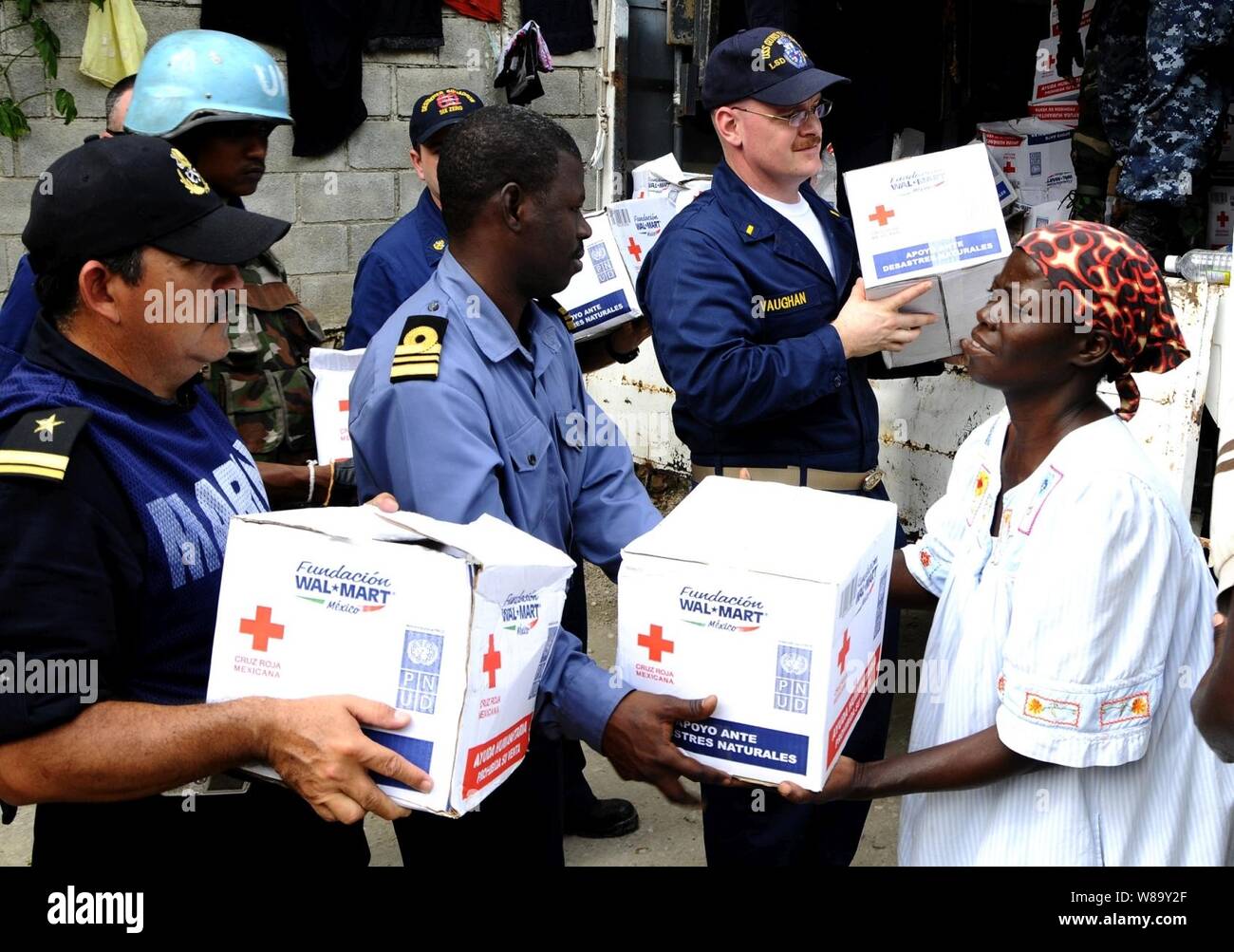 Le lieutenant de la marine mexicaine Rafael Solis Martinez (à gauche) affectés à la navire de la marine mexicaine a Huesteco bras (01), le lieutenant Cmdr. Samuel Ayelazono (centre) du Ghana, affecté à l'Africa Partnership Station West personnel à bord du navire de débarquement quai amphibie USS Gunston Hall (LSD 44), et de la Marine, l'étoile Michael Vaughan, également attribué à la Gunston Hall, distribuer de la nourriture aux habitants de Carrefour, Haïti, le 26 janvier 2010. Les fournitures ont été livrées par la marine mexicaine. Banque D'Images