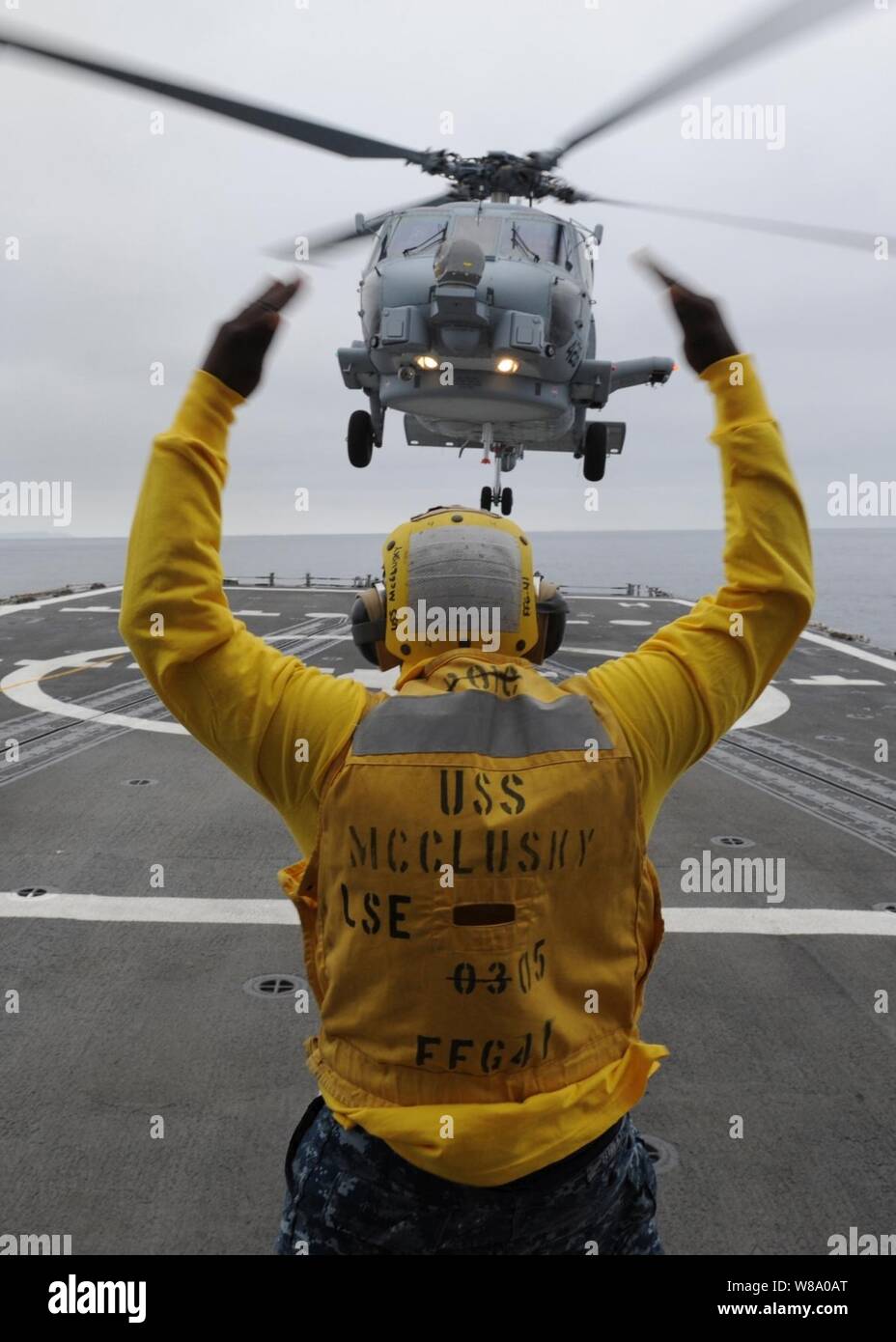 Maître de 3e classe Lazare Bullock, enrôlé à l'atterrissage à bord du signaleur frégate lance-missiles USS McClusky (FFG 41), guides un SH-60R Sea Hawk sur le poste de pilotage au cours des qualifications appontage pendant que le navire est en cours dans l'océan Pacifique le 24 juin 2011. Banque D'Images