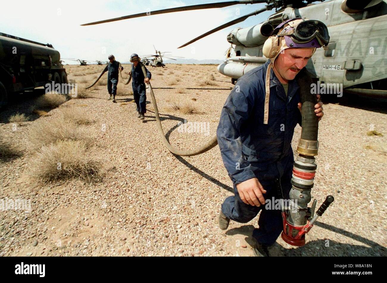 Le Cpl Marine. Paul Hardy parcours d'un tuyau de carburant d'un camion de carburant M970 à un hélicoptère à l'avant de la station-service près de Yuma (Arizona), le 17 avril 1997, au cours de l'exercice Desert Punch. Poinçon de désert est la simulation d'une mission d'assaut de l'hélicoptère portant sur plus de 60 hélicoptères de 9 escadrilles d'avions Marine Groupe 16. Les hélicoptères lancé à partir de la Marine Corps Air Station El Toro et Tustin, en Californie, et rendezvoused à l'extérieur de la zone de débarquement désignés Yuma. Des marines de l'Escadron de soutien de l'aile Marine 371, Marine Corps Air Station Yuma, mis en place et soutenu le point de ravitaillement. Banque D'Images