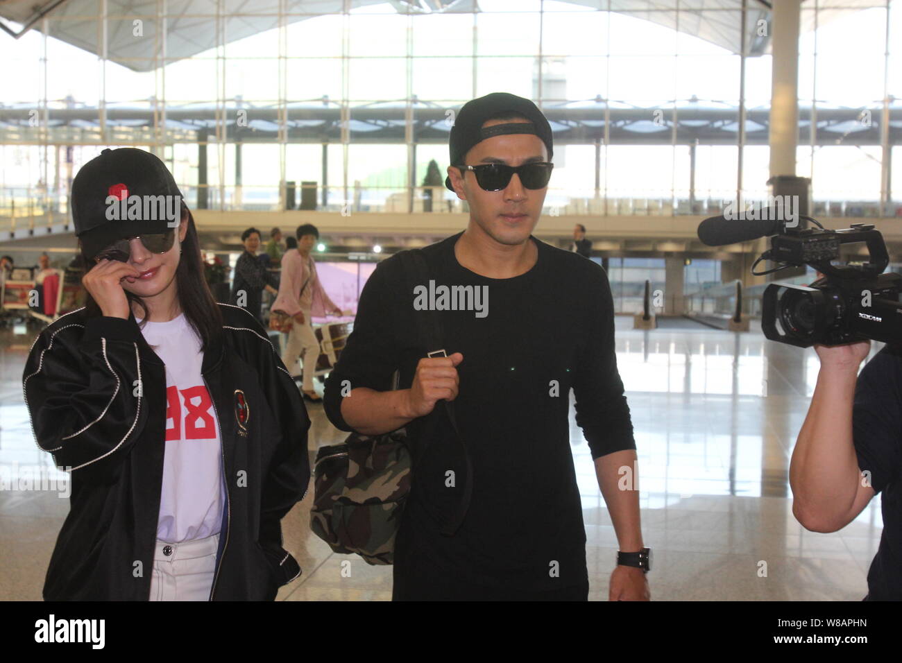 L'acteur de Hong Kong Lau, Hawick, droit accompagne son épouse, l'actrice chinoise Yang Mi à l'Aéroport International de Hong Kong avant le départ de Yang à Hong Banque D'Images