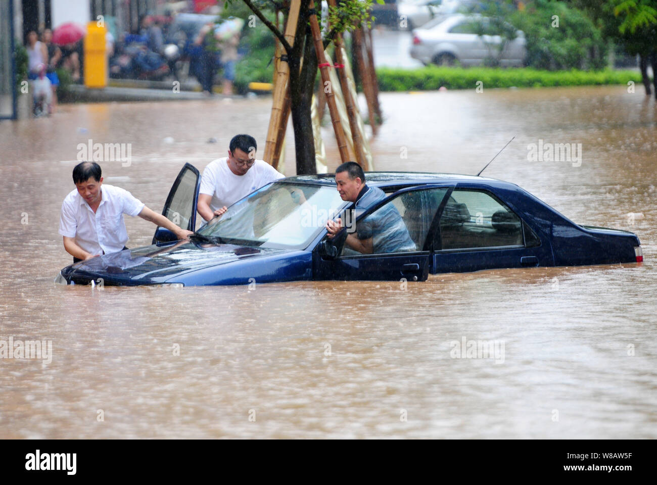 Les résidents locaux chinois poussent leur voiture sur une route inondée causées par de fortes pluies dans la ville de Jiujiang, province de Jiangxi, Chine orientale, le 15 juin 2016. R lourd Banque D'Images