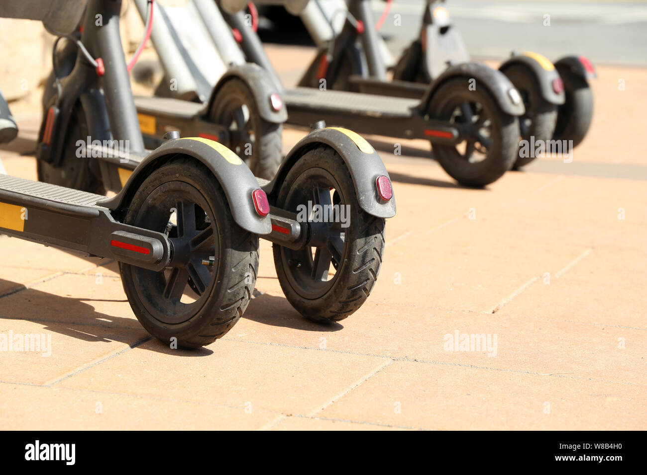 Des scooters électriques en stationnement sur une rue d'une journée ensoleillée. Système de location de transports de la ville, e-scooters sur parking Banque D'Images