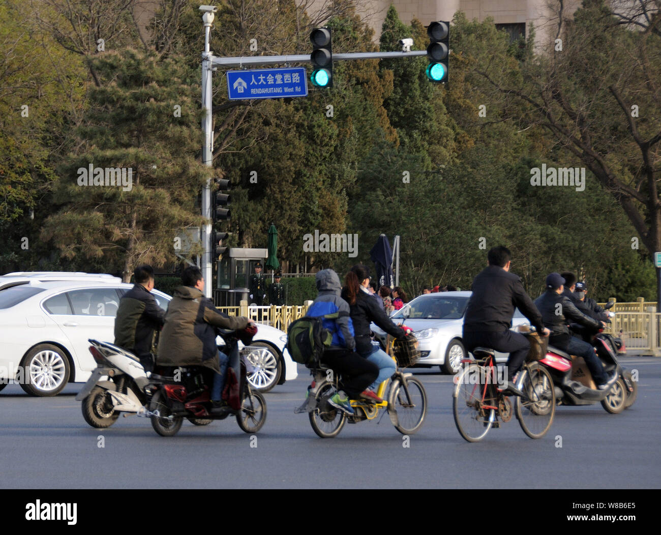 --FILE--Chinese cyclistes roulent à bicyclette ou de vélos électriques sur route, à Beijing, Chine, 7 avril 2016. Le nombre croissant de conducteurs de voiture privée est à l'o Banque D'Images