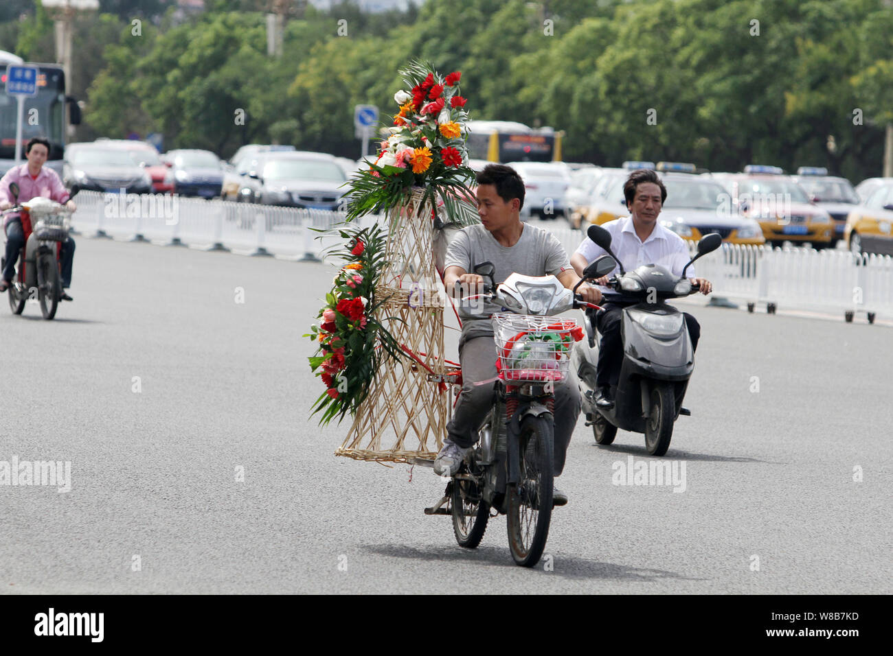 --FILE--cyclistes chinois ride vélos électrique à travers la place Tiananmen à Beijing, Chine, 3 juillet 2013. Le nombre croissant d'automobilistes je Banque D'Images