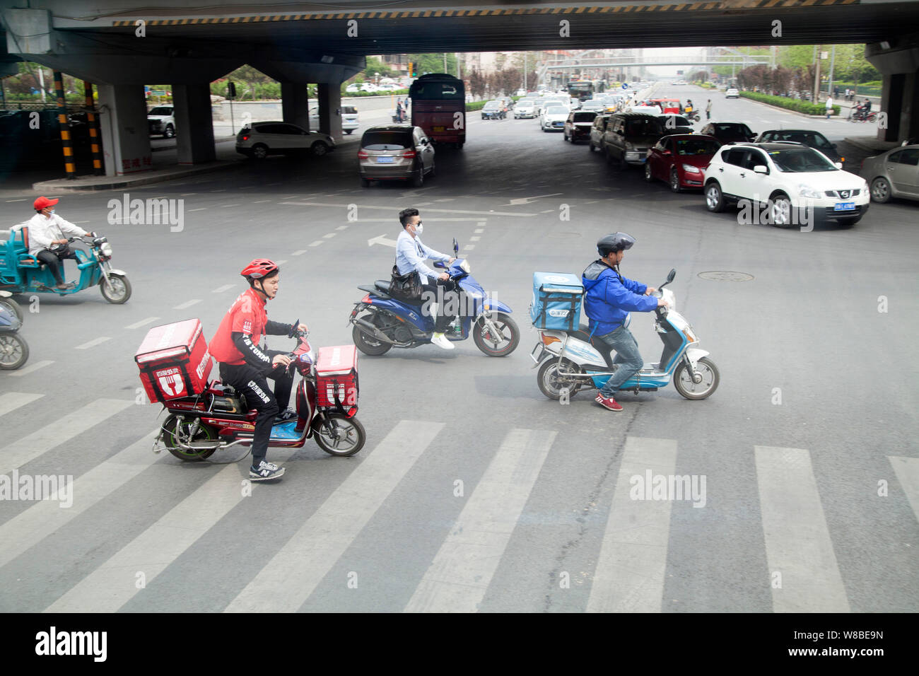 --FILE-delivermen- cuisine chinoise et d'autres cyclistes ride vélos électrique sur une route de Beijing, Chine, 13 avril 2016. Le nombre croissant de parking Banque D'Images
