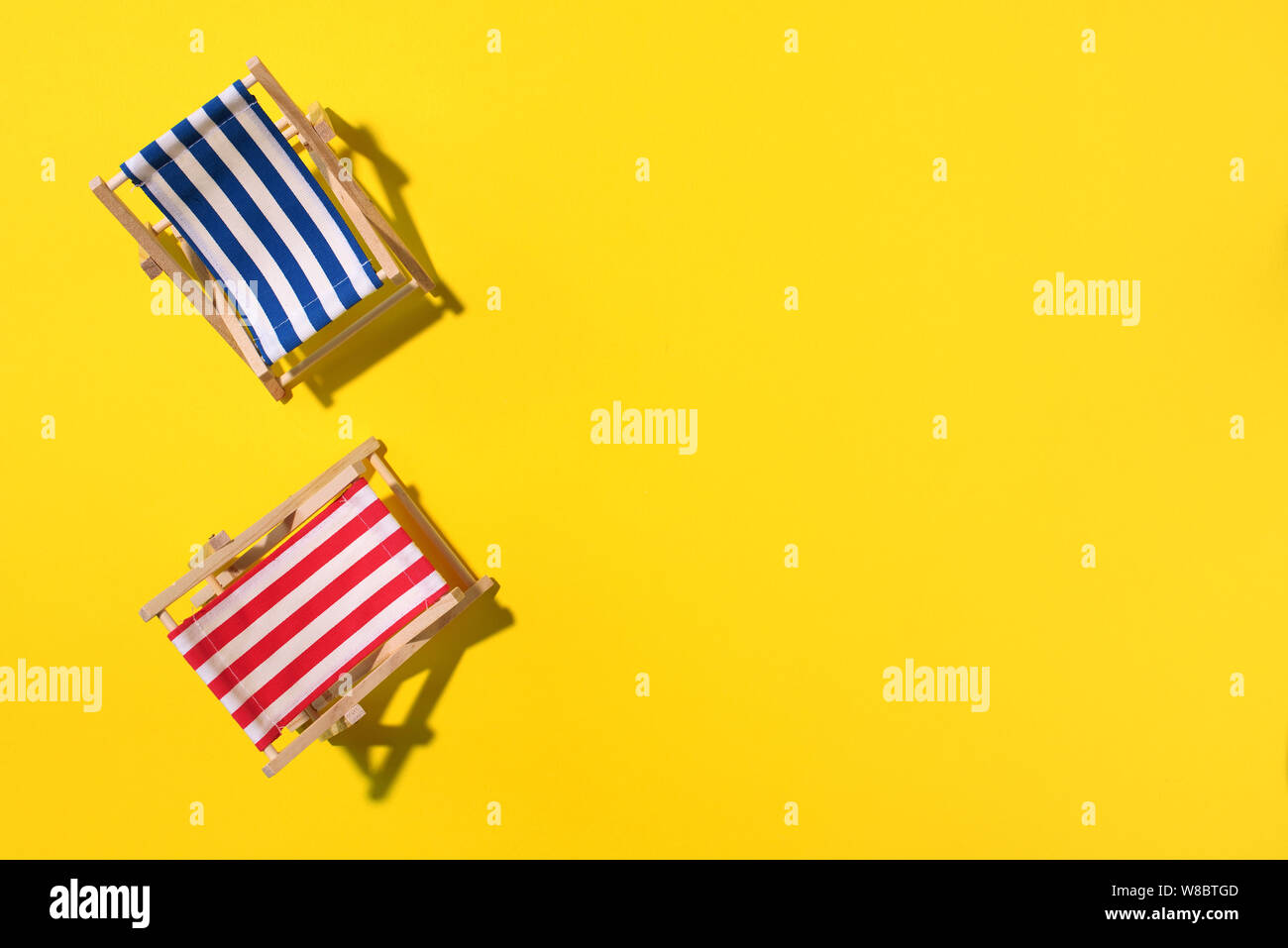 Deux chaises longues avec ombre, monstera et de feuilles de palmier sur du papier jaune arrière-plan. Mise à plat et de copier l'espace. Été voyage vacances concept. Composition minimale. Banque D'Images
