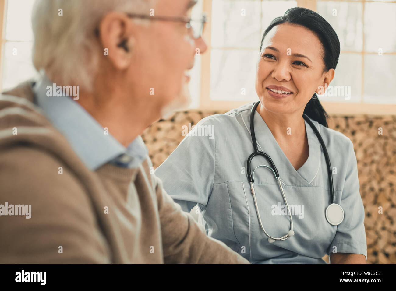 Smiling genre femme médecin à la sur son ancien patient Banque D'Images