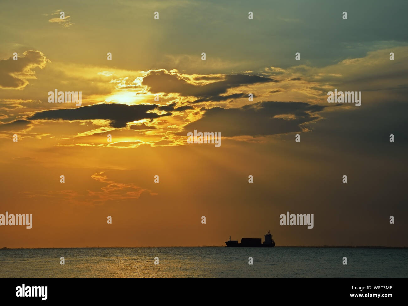 Silhouette d'un cargo au coucher du soleil avec ciel dramatique Banque D'Images