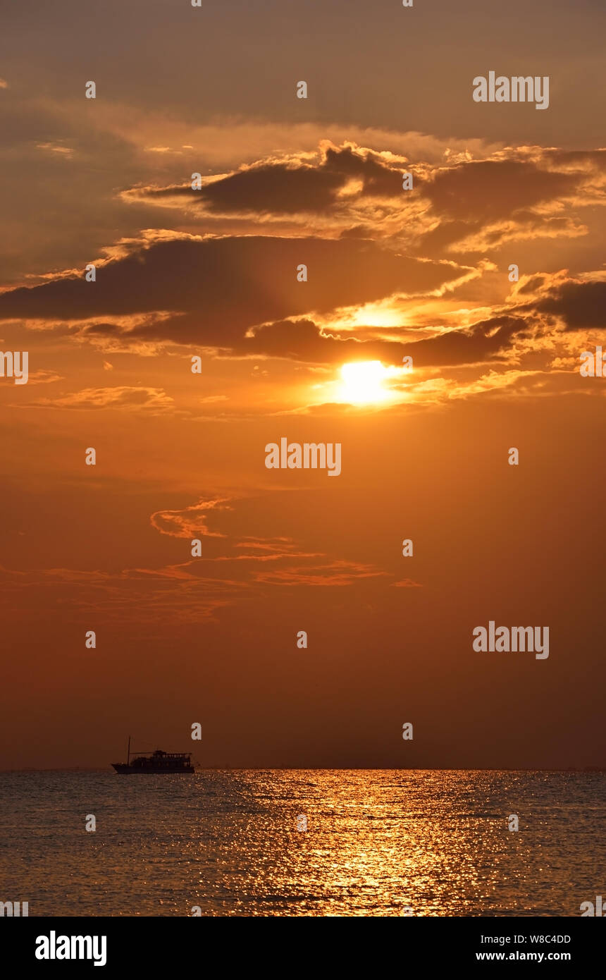 Silhouette de petit bateau au coucher du soleil jaune Banque D'Images