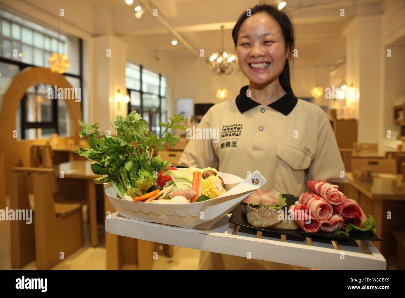 Une serveuse présente le contenu d'une potée d'être préparé dans un récipient en papier dans un restaurant dans l'histoire 'papier' dans la ville, Minhang District, Shanghai Banque D'Images