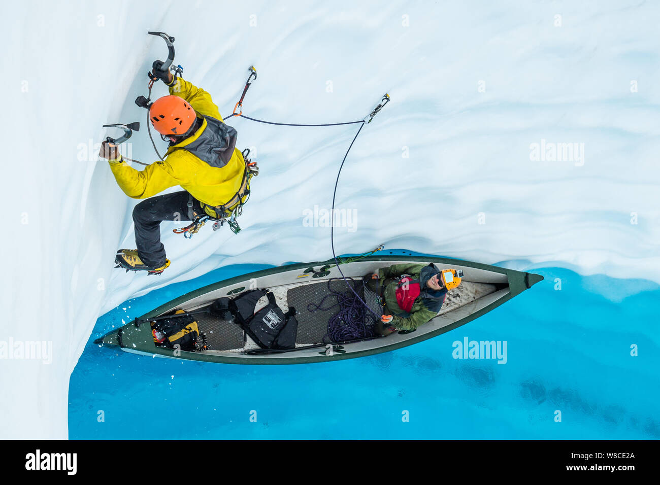 Grimpeur sur glace à venir d'un bateau gonflable dans une piscine bleue sur le Glacier Matanuska en Alaska. Il dirige au-dessus de la voile en plaçant les vis de la glace comme il le clim Banque D'Images