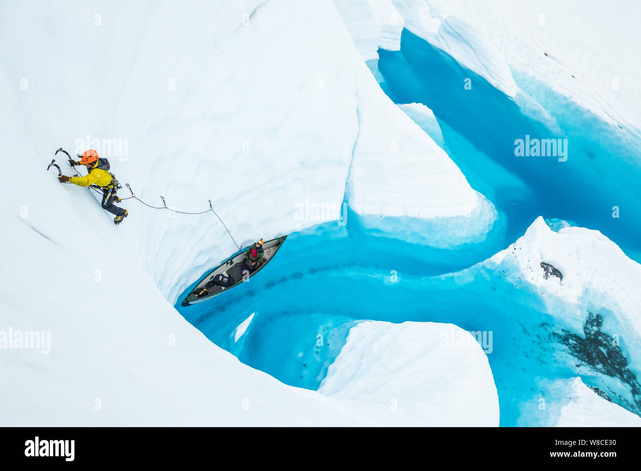 Jeune homme l'escalade de glace sur la tête de file d'un canot sur l'eau d'un lac Glacier Matanuska en Alaska. Banque D'Images