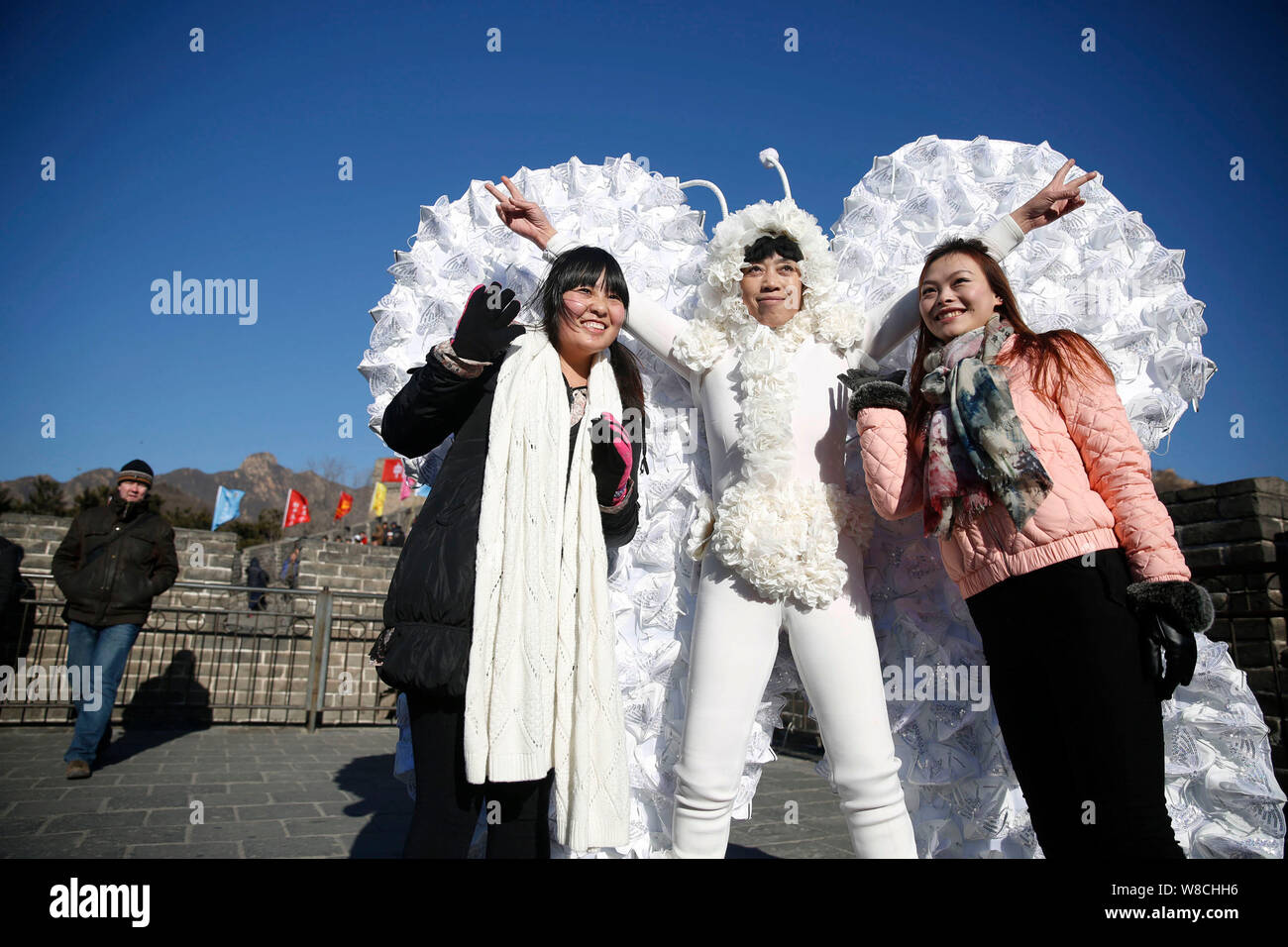 L'artiste chinois Kong Ning, droit, vêtu d'un costume de papillon fait avec 365 masque de visage pose avec les visiteurs à la Grande Muraille de Badaling sur le outskir Banque D'Images