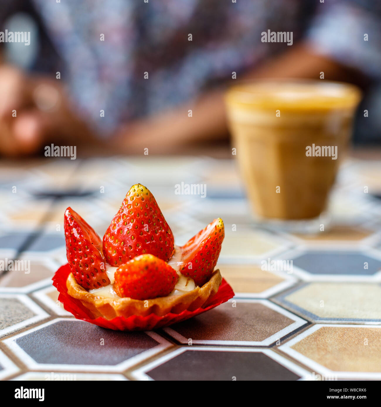 Un verre de café au lait et une tarte aux fraises sur une table en céramique colorée dans un café. Image carrée. Banque D'Images