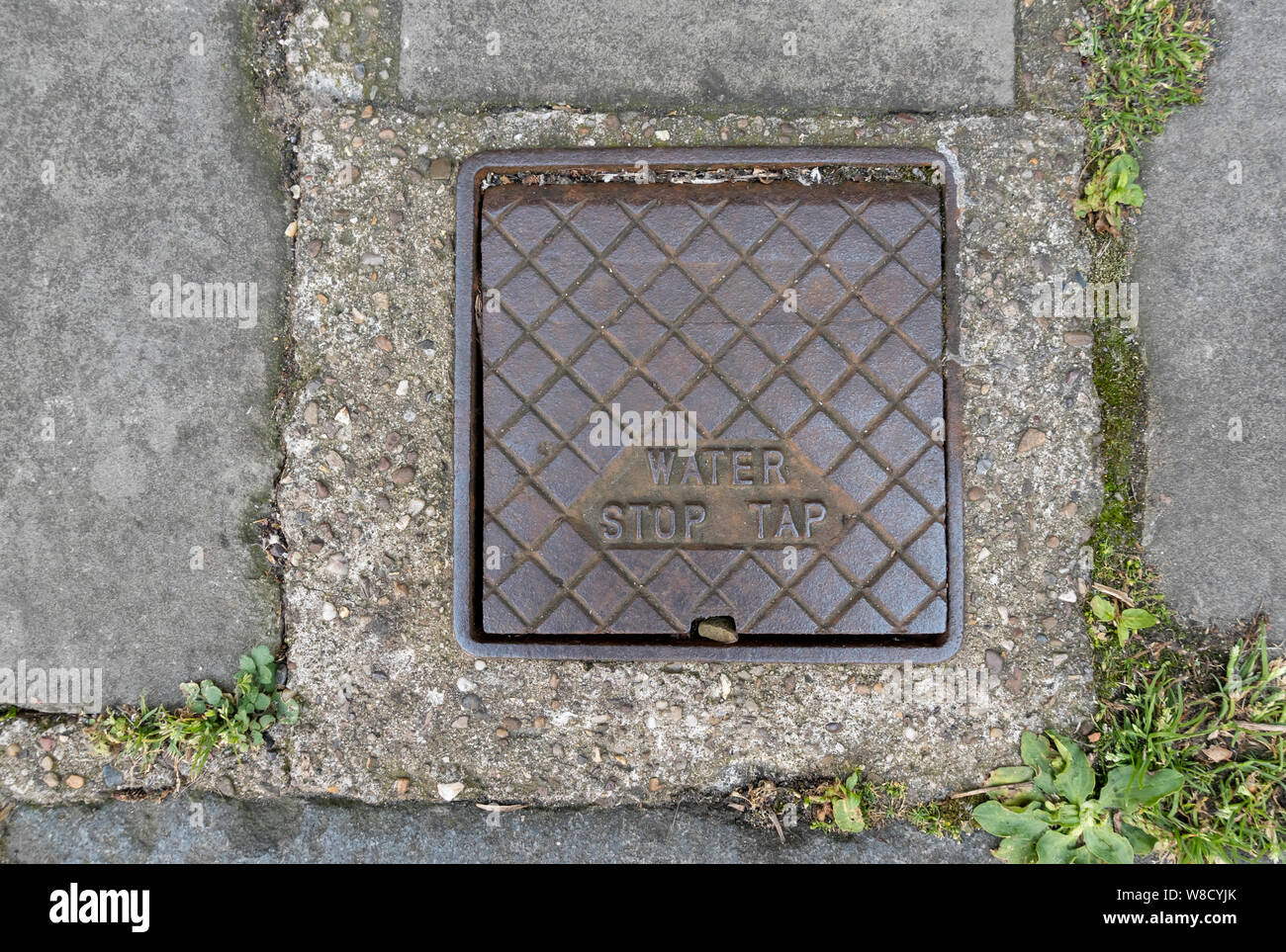 Gros plan de l'ancien robinet d'arrêt d'eau alimentation secteur couvercle plaque de couvercle dans un chemin Angleterre Royaume-Uni Royaume-Uni Grande-Bretagne Banque D'Images