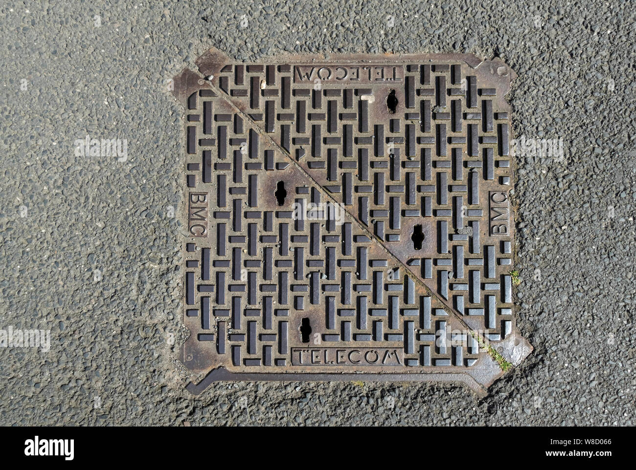 Gros plan de la couverture de trou d'accès à l'inspection en fonte britannique BMC Telecom Telecommunications dans un sentier Angleterre Royaume-Uni Grande-Bretagne Banque D'Images