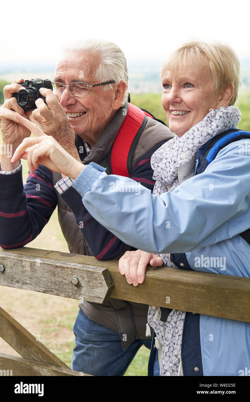 Senior Couple Hiking in Countryside debout près de la porte et la prise de photo avec l'appareil photo Banque D'Images