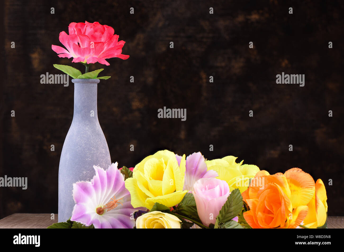 Fleurs artificielles multicolores de types différents sur une table en bois. Banque D'Images
