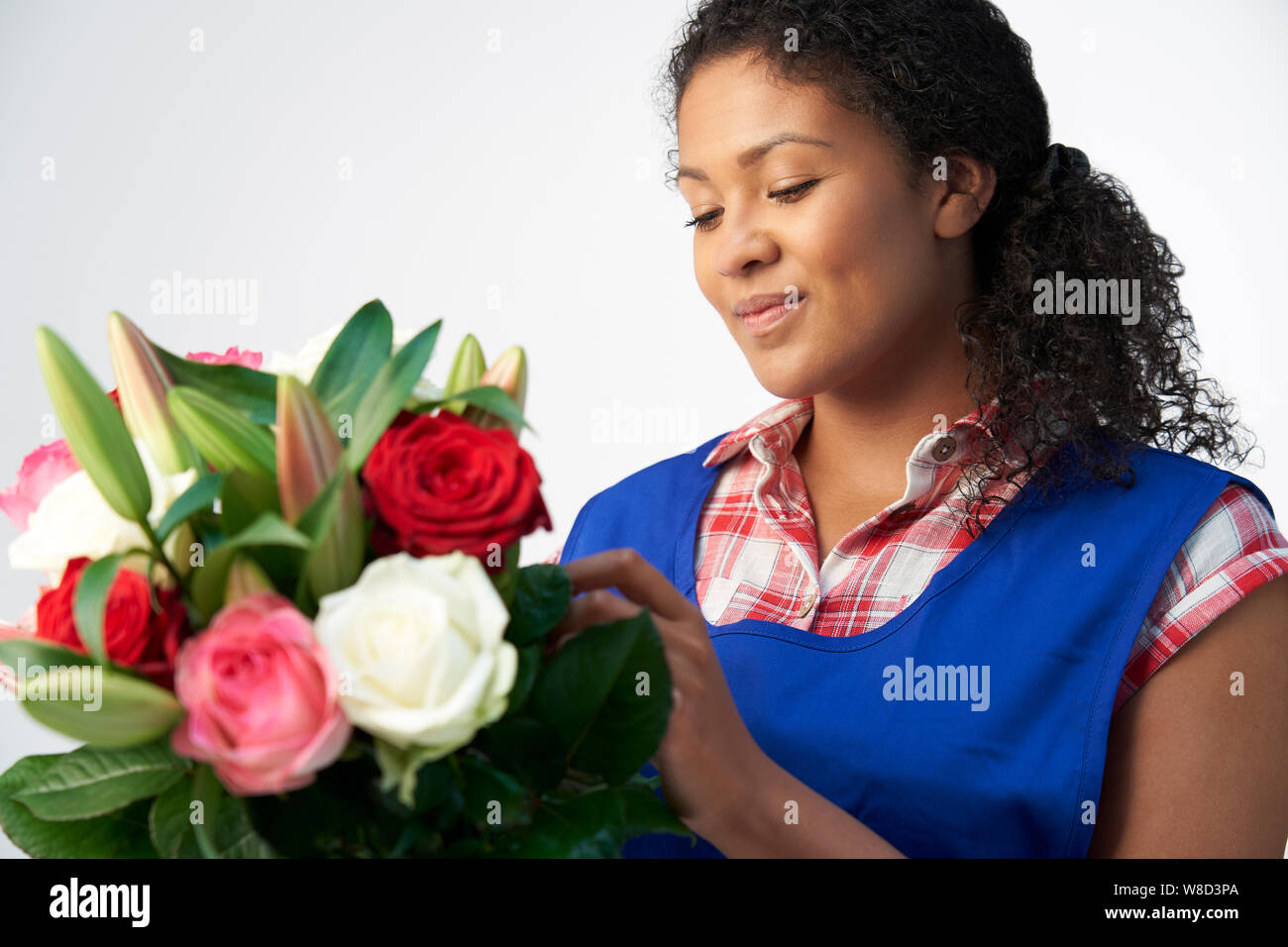 Studio Shot of Female Florist Organisation Bouquet de roses et Lys Against White Background Banque D'Images