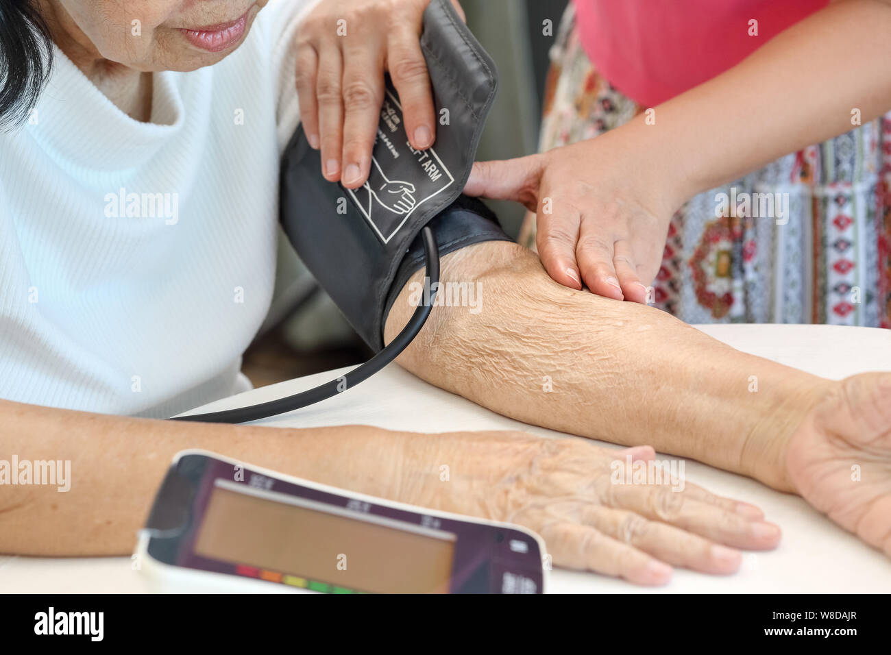 Fille contrôle de la pression artérielle (hypertension) de personnes âgées à la maison mère Banque D'Images