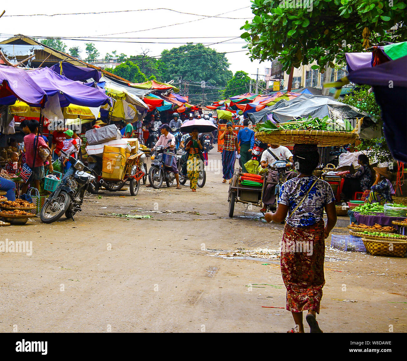 Vieille Femme avec un grand panier sur sa tête sur un marché coloré de Yangon, Myanmar/Birmanie. Banque D'Images