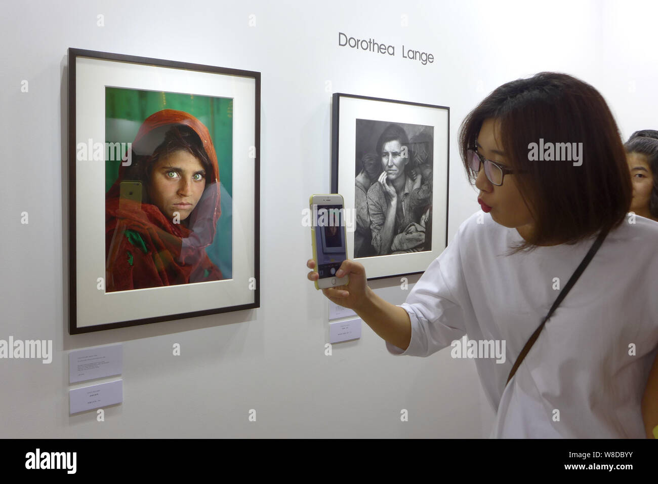 Un visiteur prend une photo de la photo 'fille afghane' par Steve McCurry, photographe américain de l'afficheur pendant un essai de la photo Shanghai 201 Banque D'Images
