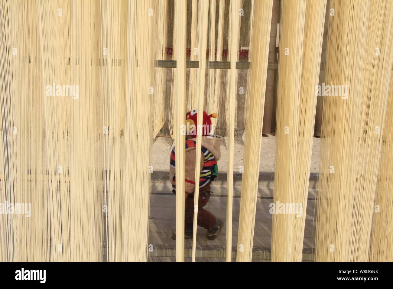 Un jeune Chinois kid marche dernières belles nouilles sèches dans le cadre d'un atelier en Huangxian county, ville d'Anyang, province du Henan en Chine centrale, 14 février 2015. Banque D'Images