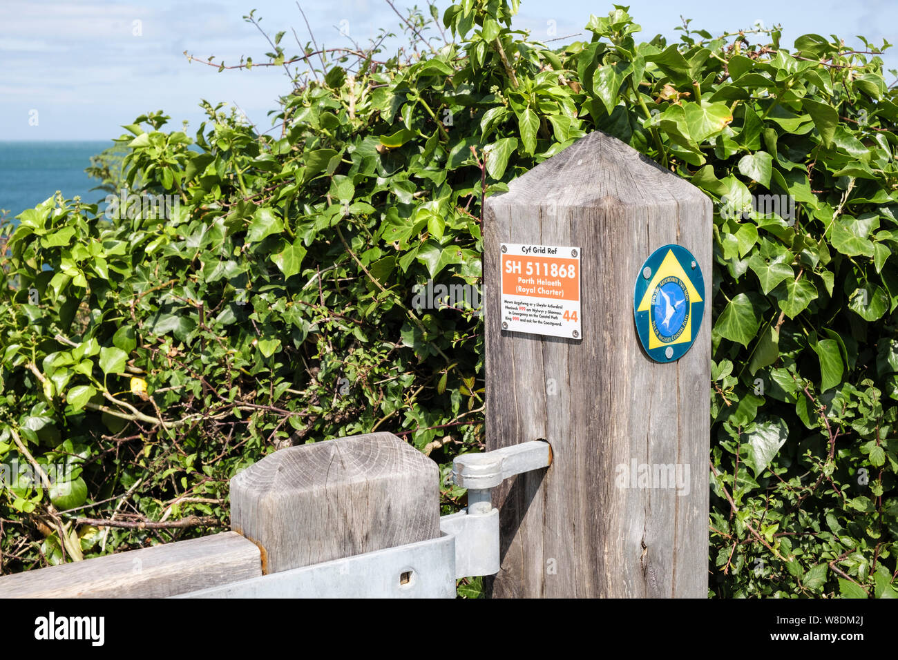 Marqueur de référence grille affiche bilingue sur Anglesey Coastal Path gate post avec informations d'urgence. Helaeth Porth Llangefni Isle of Anglesey Pays de Galles UK Banque D'Images