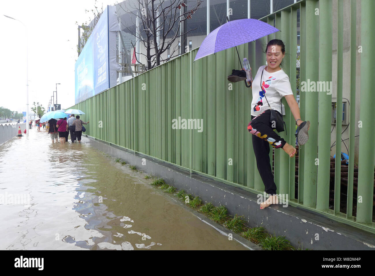 Un piéton marche sur une clôture sur une route inondée dans une forte pluie causés par le typhon Goni à Shanghai, Chine, 24 août 2015. Shanghai est devenu un wat Banque D'Images