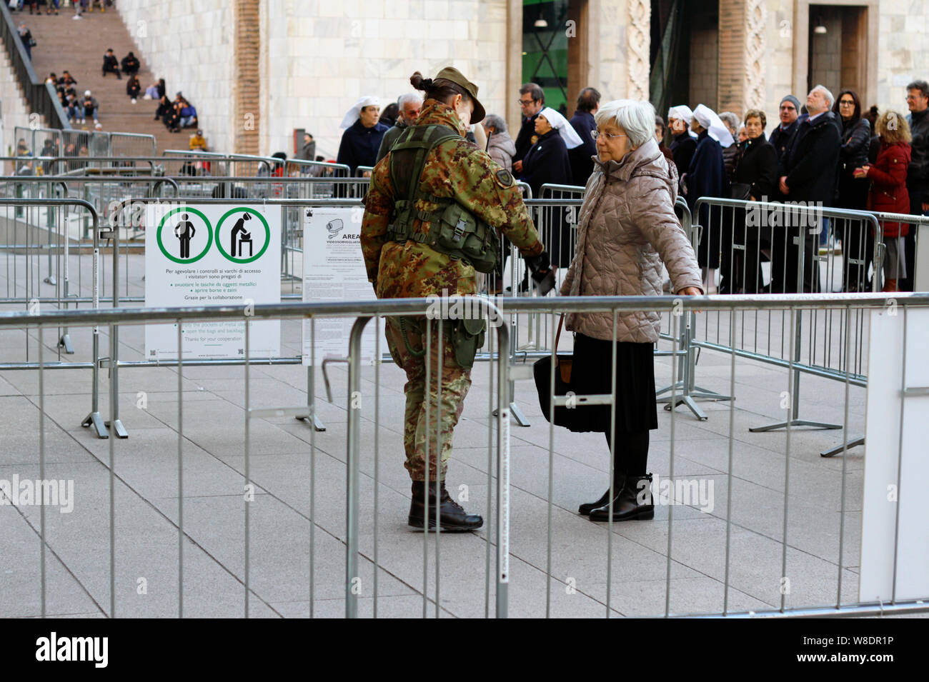 Milan, Italie - 14 décembre 2018 : A senior woman est fouillée par un soldat vêtu d'un uniforme de camouflage avant d'entrer dans la cathédrale de Milan. Banque D'Images