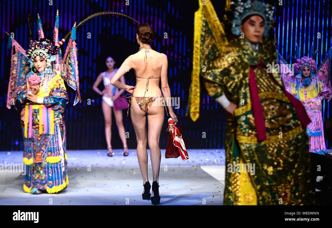 Un modèle en maillot affiche un sac de luxe comme acteurs de l'Opéra de Pékin effectuer sur la même scène lors d'un défilé dans la ville de Jinan, est de la Chine.s Shandon Banque D'Images