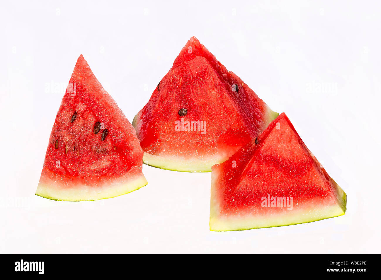 Trois cales triangulaires de pastèque fraîche sur un fond blanc. Banque D'Images