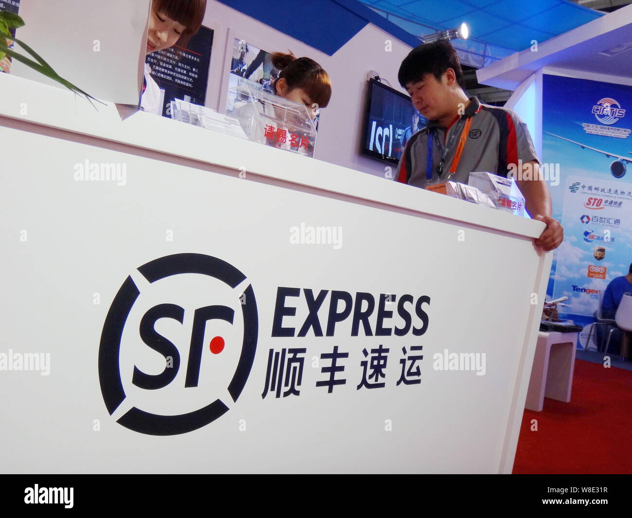 --FILE--Employés Chinois parlent au stand de SF Express pendant une exposition à Beijing, Chine, 29 mai 2013. SF Express, express chinois de premier plan Banque D'Images