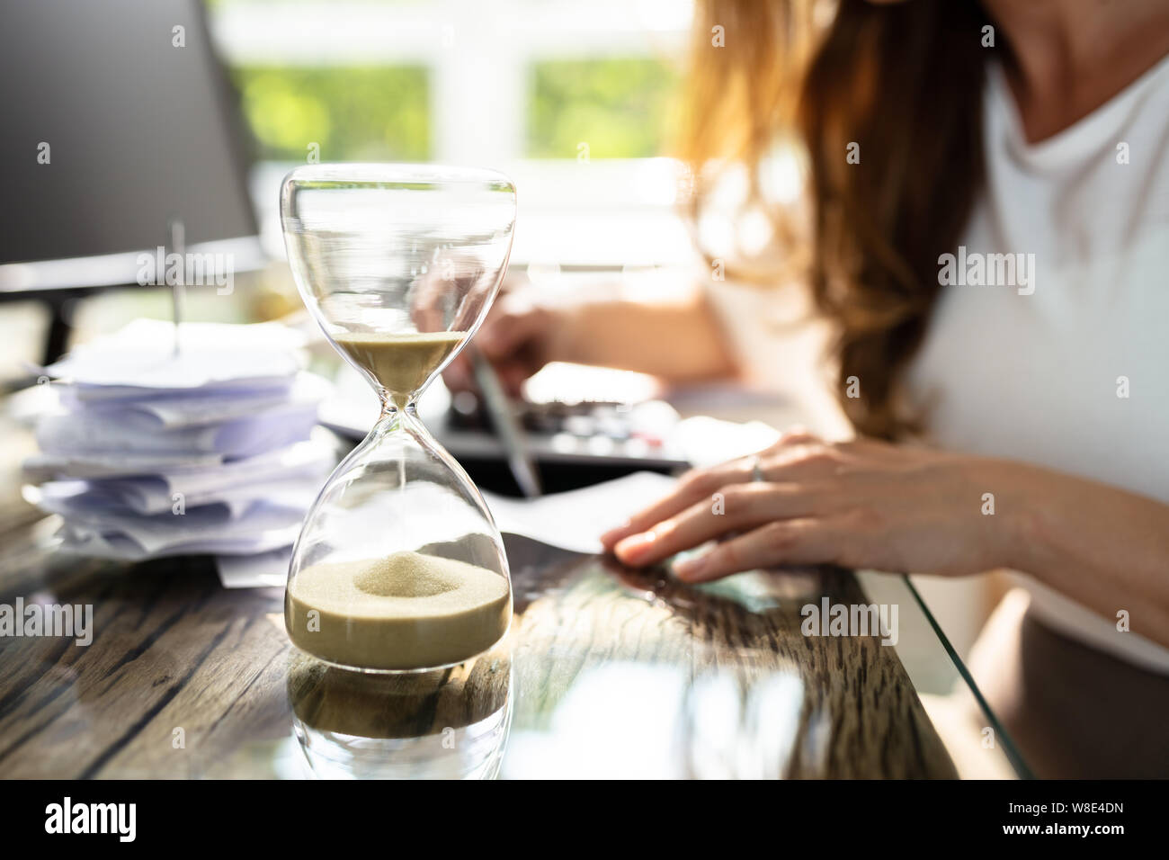 Close-up d'un sablier en face de Businesswoman Working in Office Banque D'Images